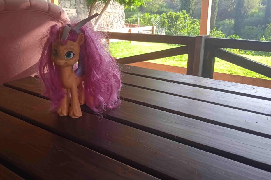 „Spielzeug-Einhorn mit rosa Mähne und großen blauen Augen auf Holztisch – symbolisches Bild für die Geschichte ‚Chatty und das Stöckchen‘.“