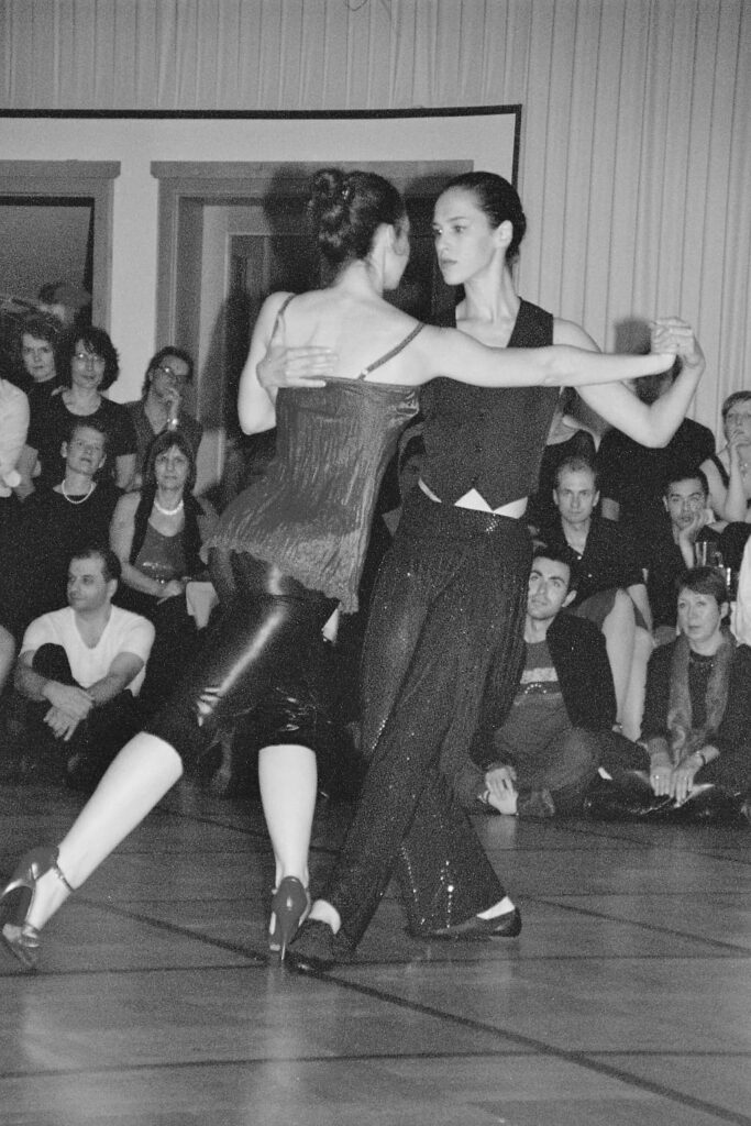 Zwei Frauen tanzen Tango, eine führt, die andere folgt – Bühnenauftritt in Schwarz-Weiß“, neustart50