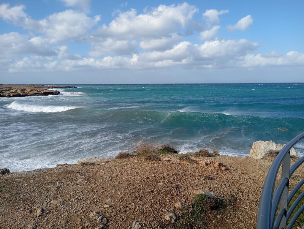 Türkisfarbene Wellen an der Sardunya Bay unter wolkigem Himmel