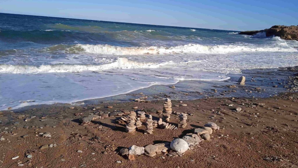 Steinmännchen am Strand vor einem unruhigen Meer