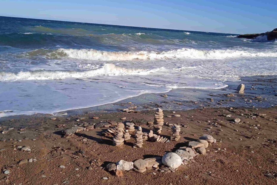 Steinmännchen am Strand vor einem unruhigen Meer
