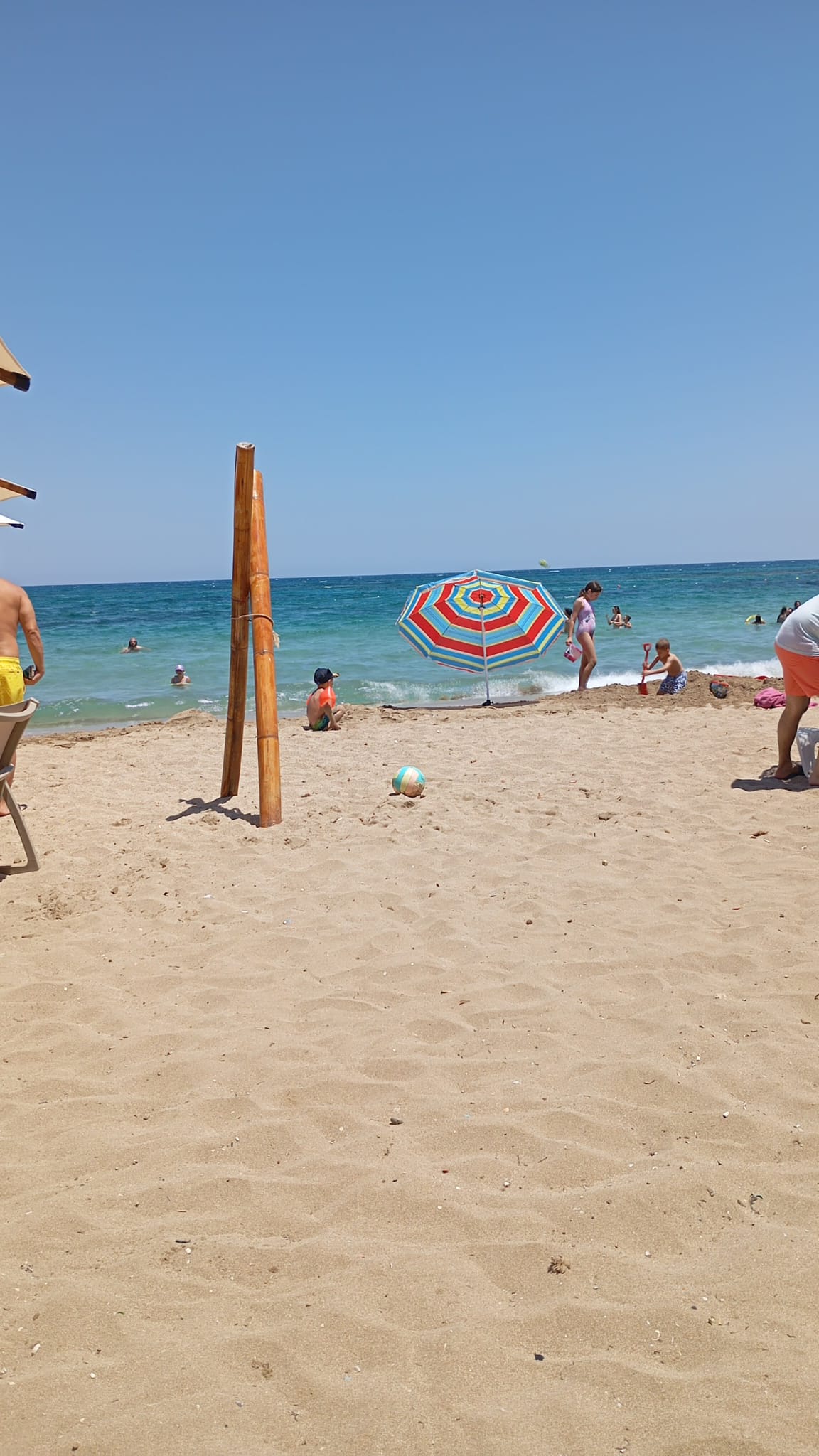 Kinder spielen und buddeln an einem belebten Sandstrand.